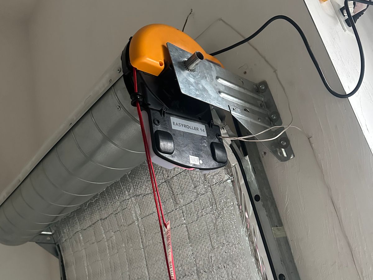 Orange EasyRoller garage door opener installed with emergency release on residential ceiling
